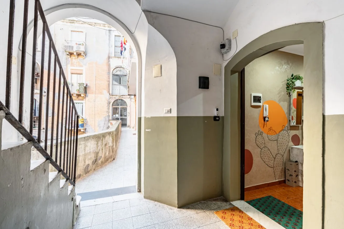 An arched interior passage opens onto a stairway and a tiled room.
