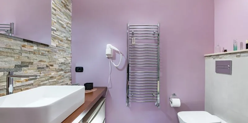 A bathroom with a white basin, wall-mounted towel warmer, and toilet.