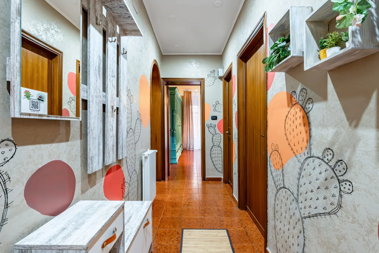 A narrow hallway with wooden doors, patterned walls, and built-in storage.