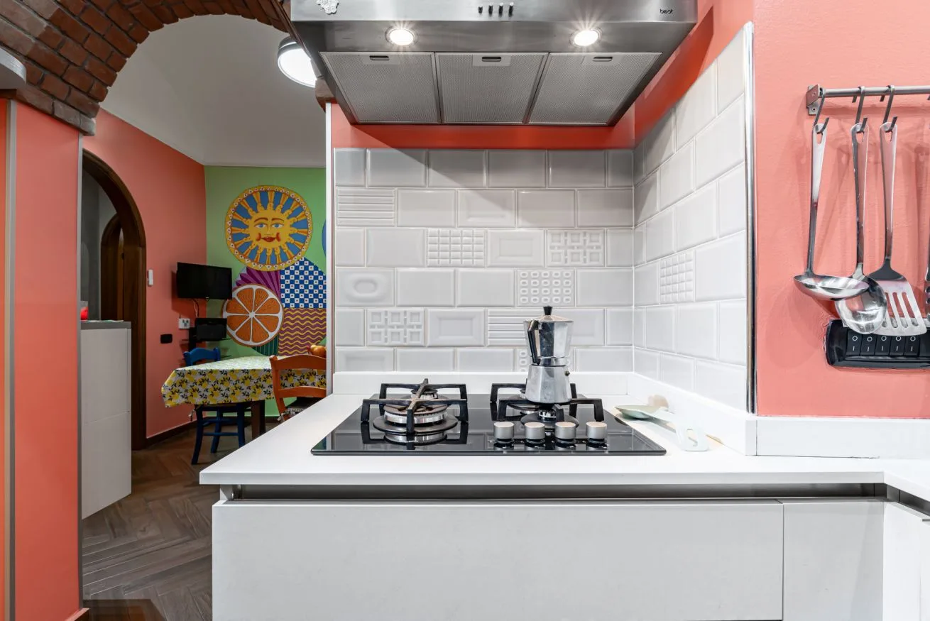 A modern kitchen with a gas cooktop and white tiled backsplash.
