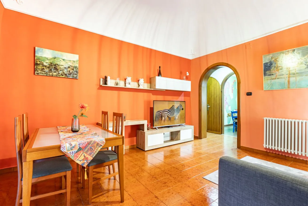 A living and dining area with orange walls, a wooden table, and seating.