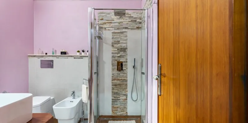 A bathroom with a glass shower, toilet, and sink.