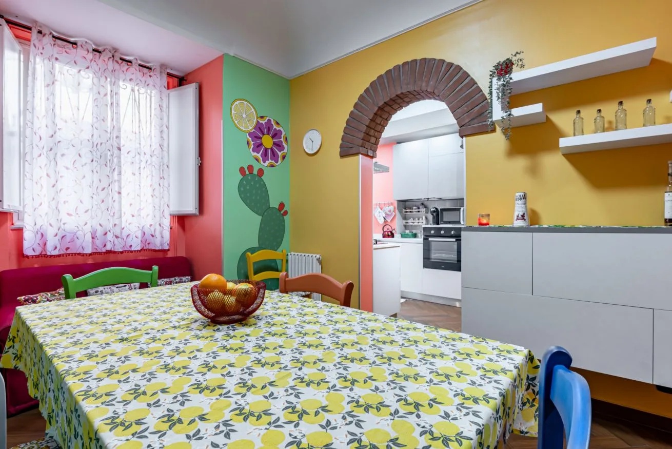 A dining area with a patterned tablecloth beside a kitchen.