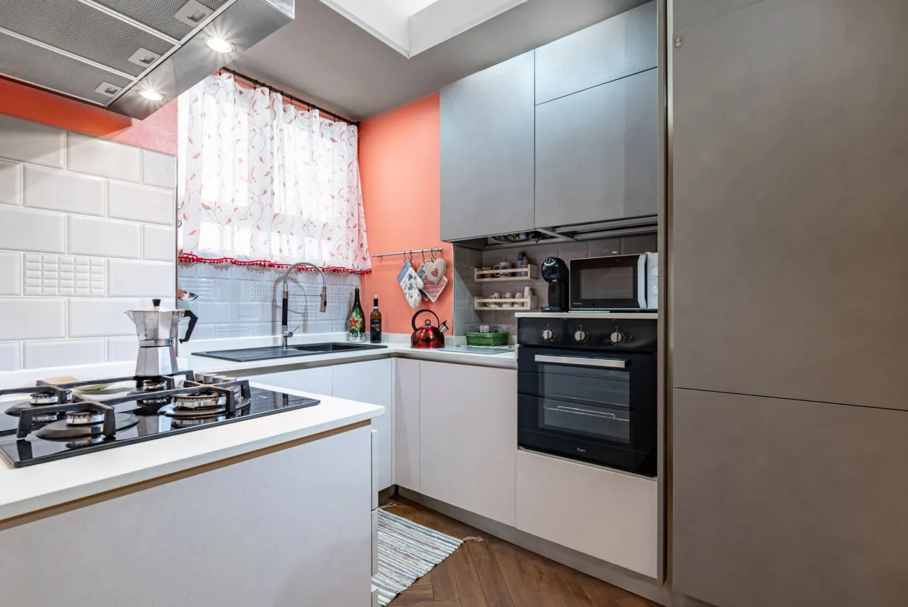 A modern kitchen with a stovetop, sink, and gray cabinets.
