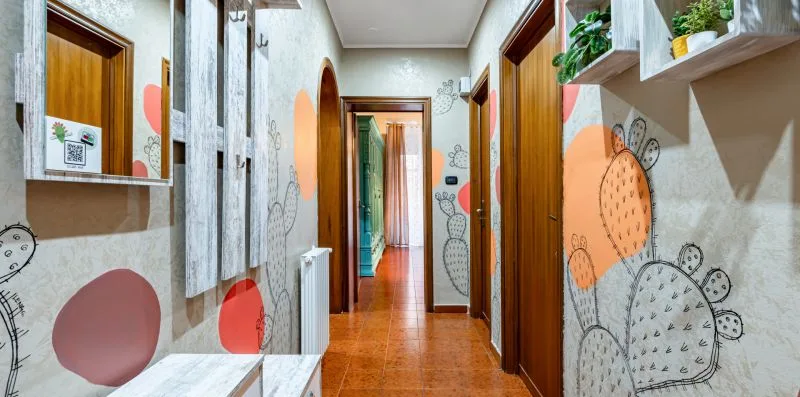 A narrow interior hallway with colorful wall decorations and wooden doors.