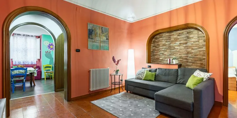 A living room with a gray sectional sofa and orange walls.
