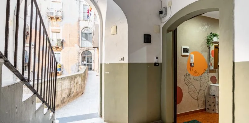 An arched hallway opens onto a stairway and a small tiled room.