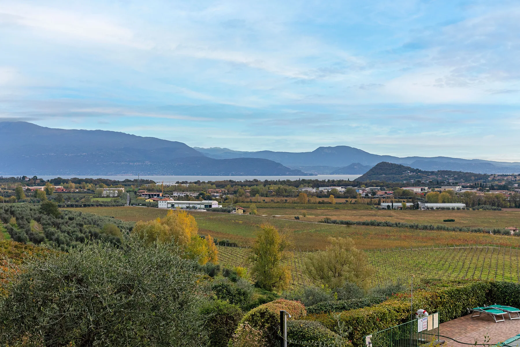 Una vista amplia de campos y viñedos se extiende hacia montañas lejanas bajo un cielo nublado.