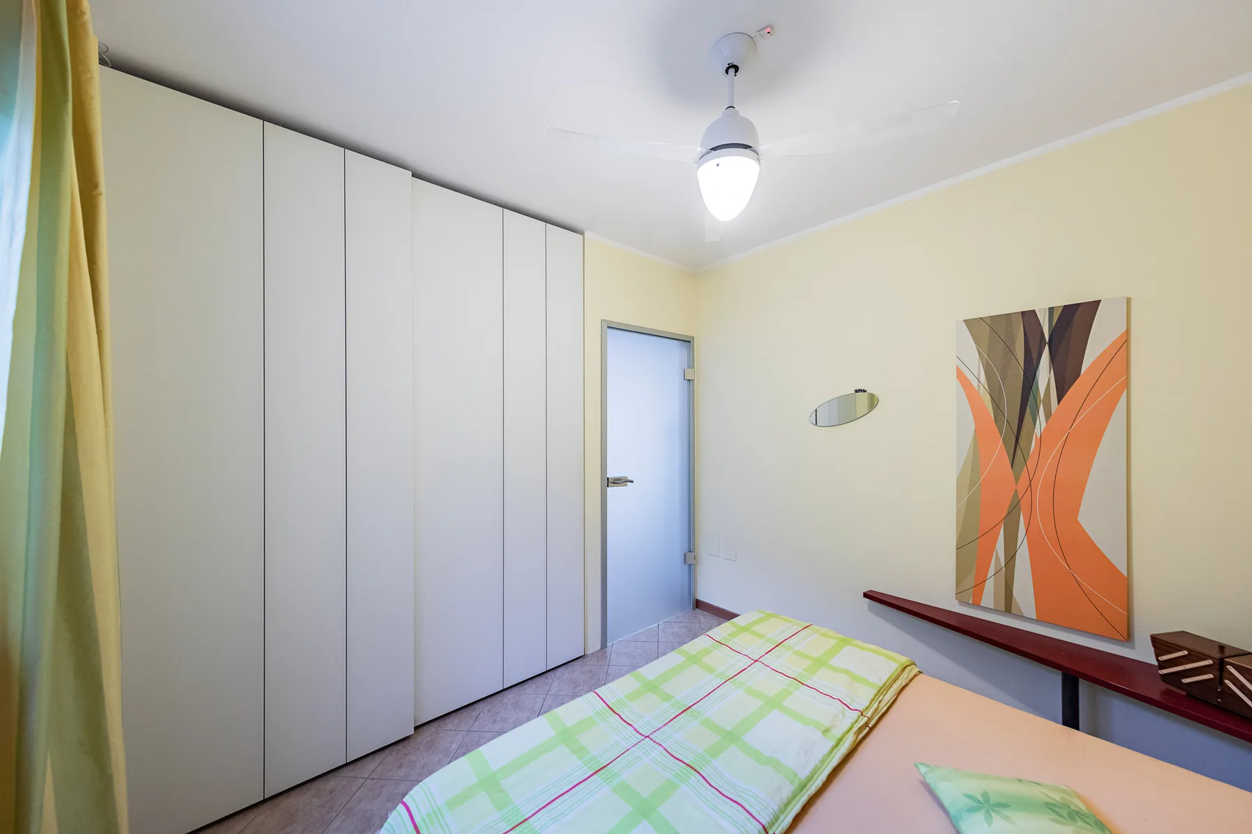 Un dormitorio con una cama, armarios empotrados y arte abstracto en la pared.
