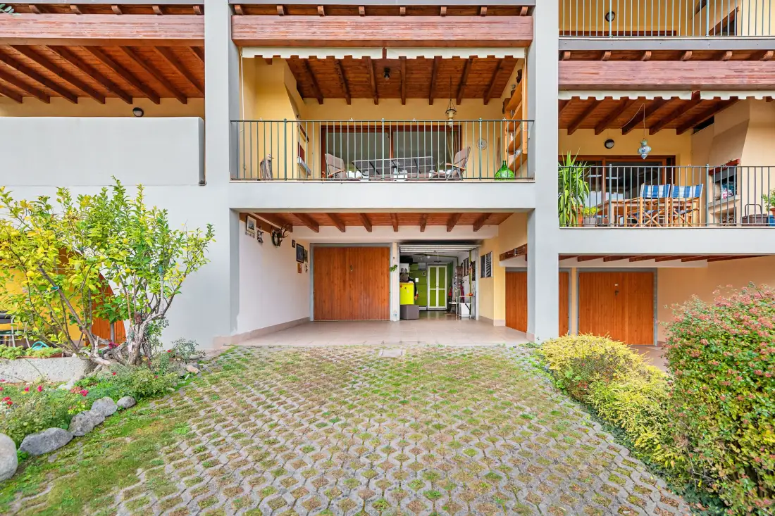 Un edificio de varios niveles da a un patio pavimentado con plantas.