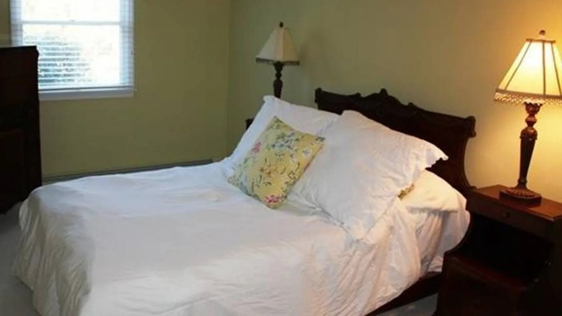 Un dormitorio con una cama vestida de blanco y una lámpara de noche.
