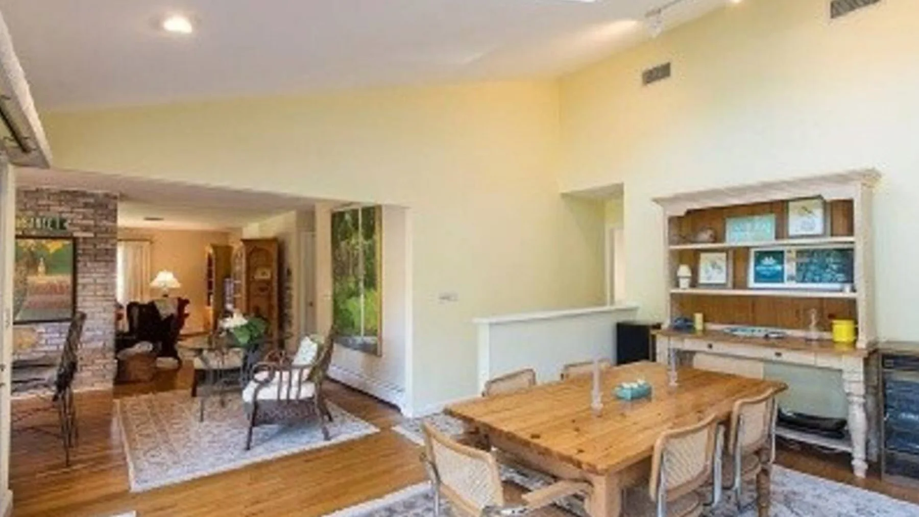 Un espacio abierto de comedor y sala con una mesa de madera y asientos.