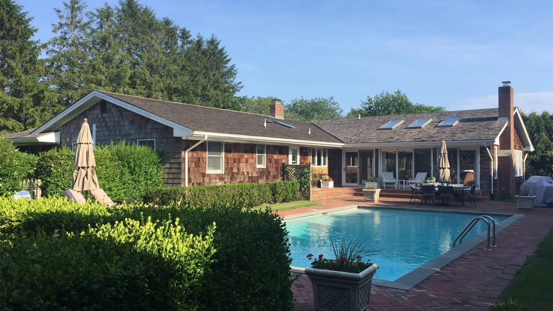 Una casa con piscina y jardín ajardinado.