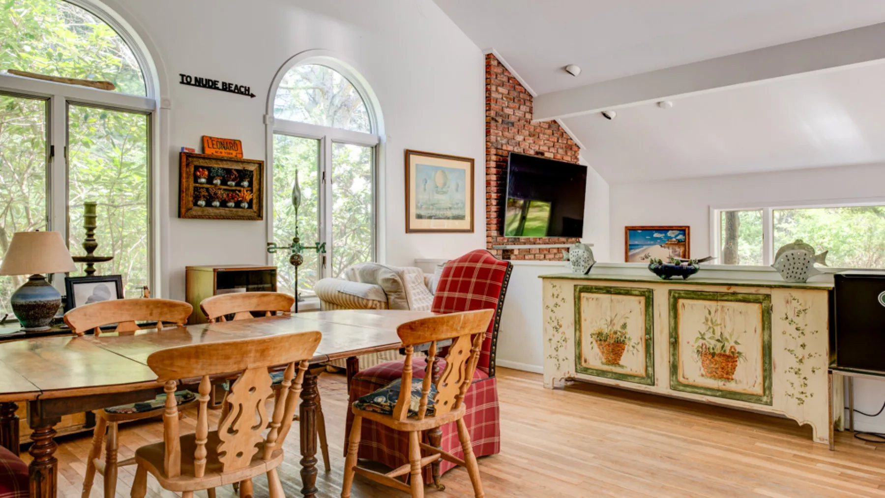 A bright dining area opens into a kitchen with a long counter and leafy views.