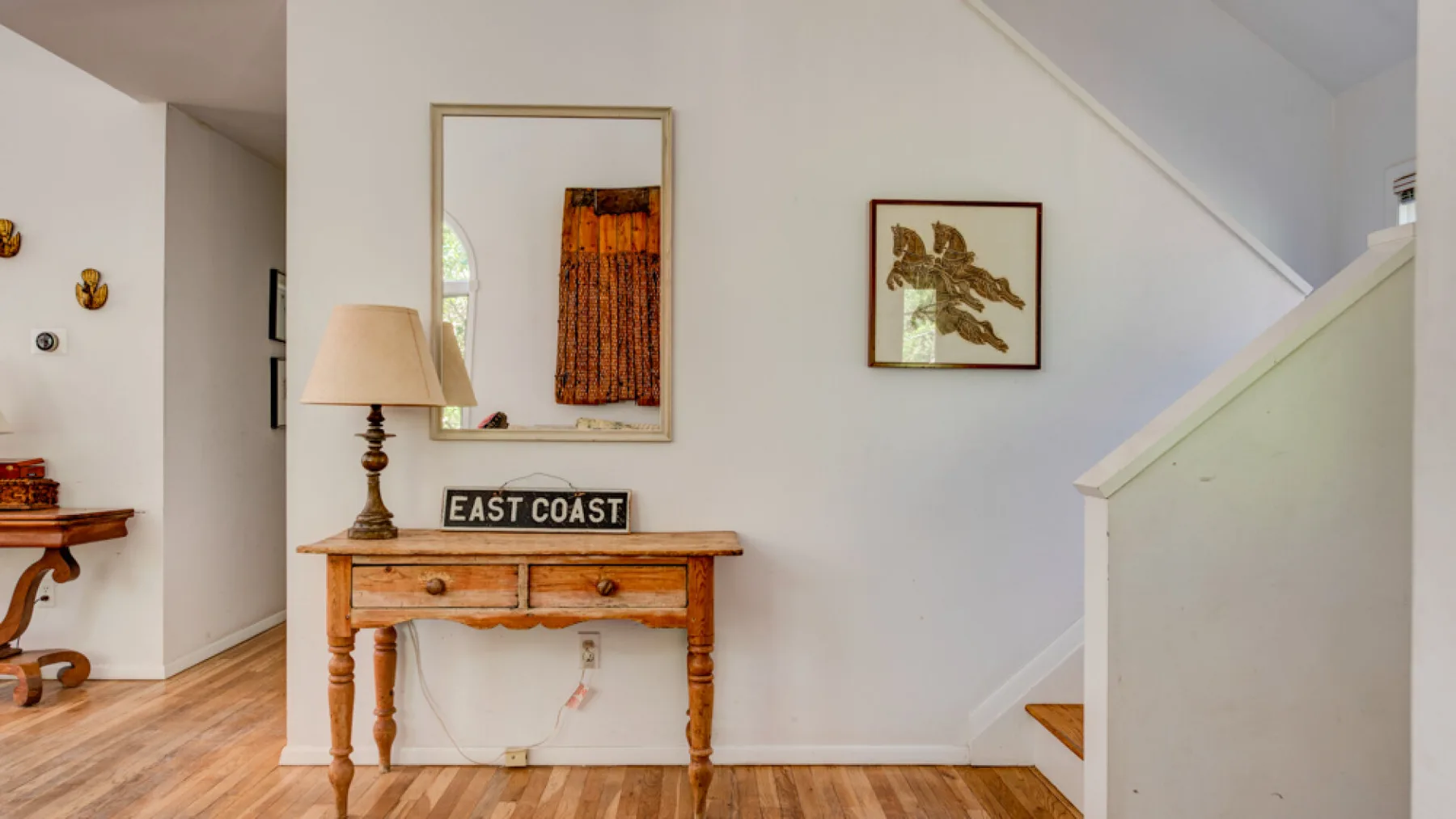 A bright interior hallway with a wooden console table and framed artwork.