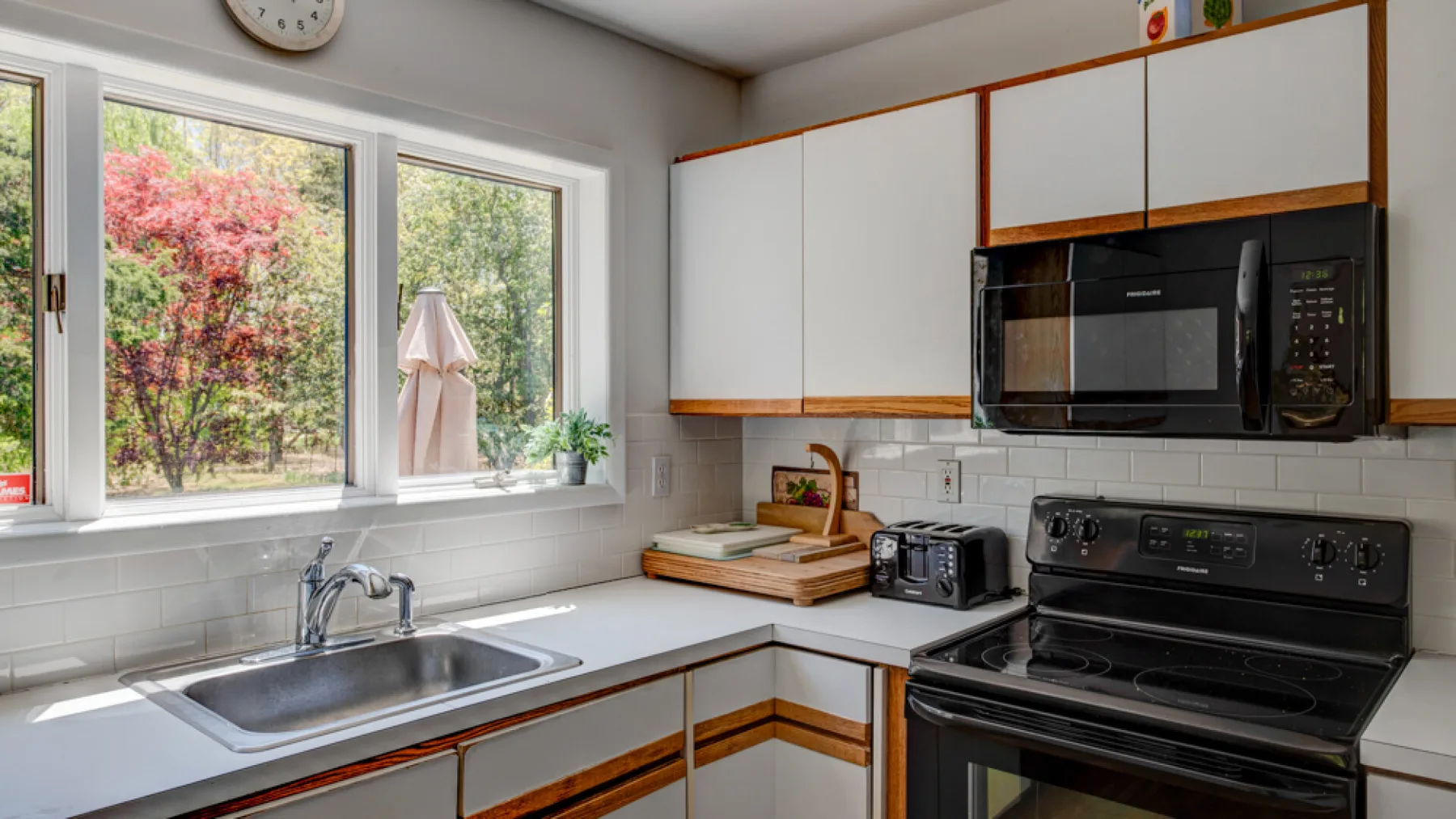 A bright kitchen with a sink beneath windows and a stove along the counter.