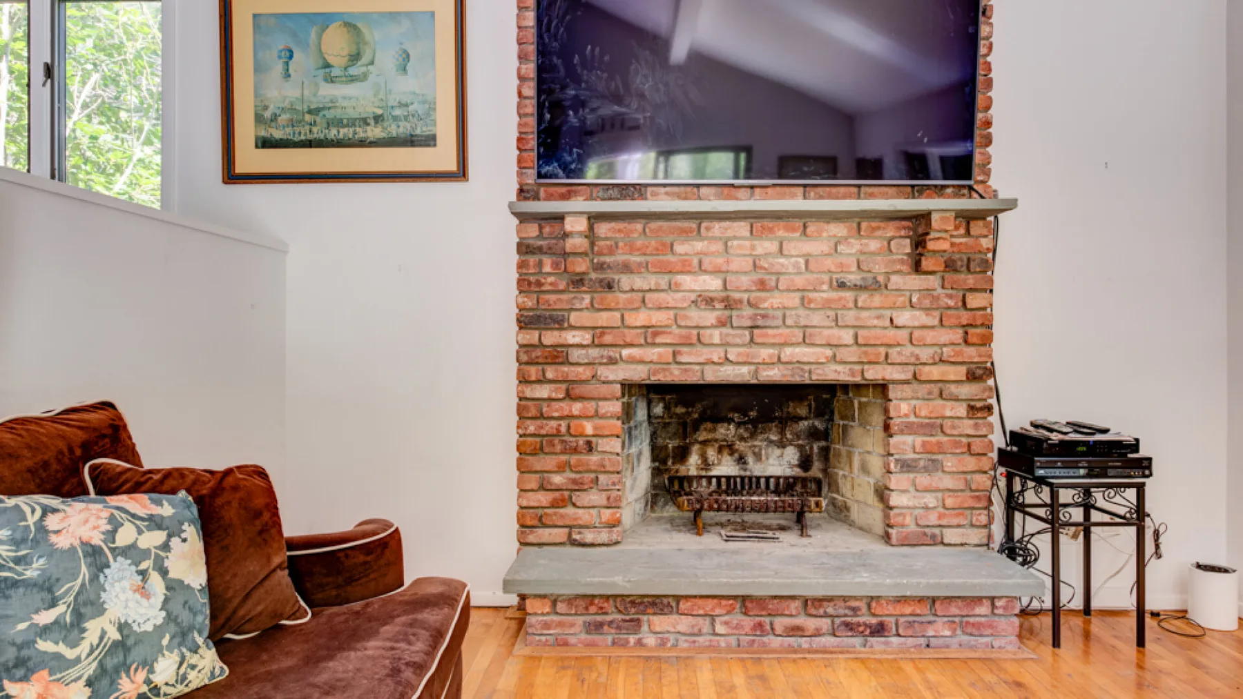 Una sala de estar con una chimenea de ladrillo y una obra enmarcada en la pared.
