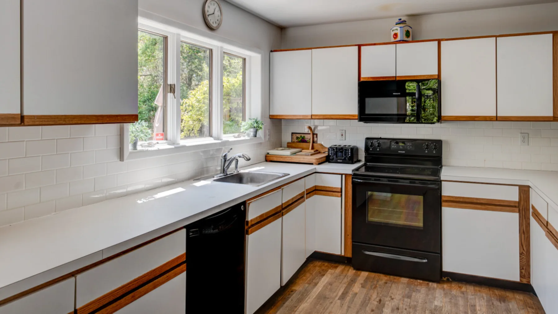 A bright kitchen with white cabinets, a countertop, and a black stove.