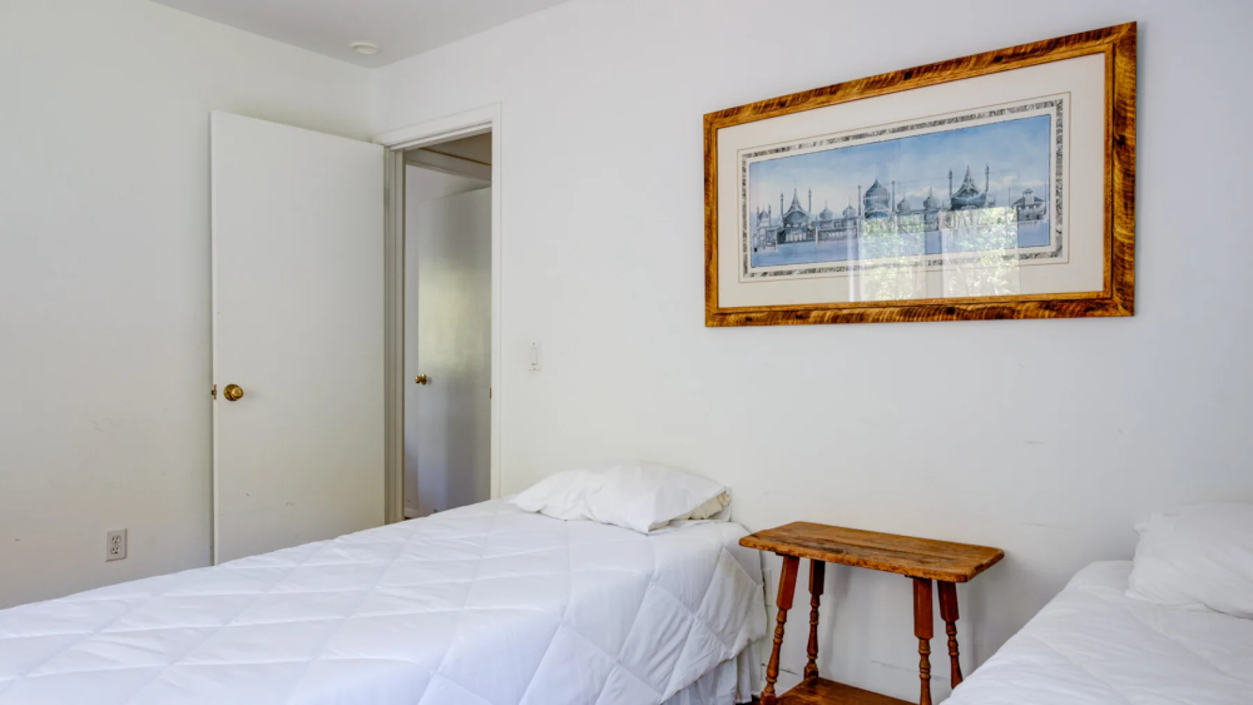 A bedroom with two beds and a framed picture on the wall.