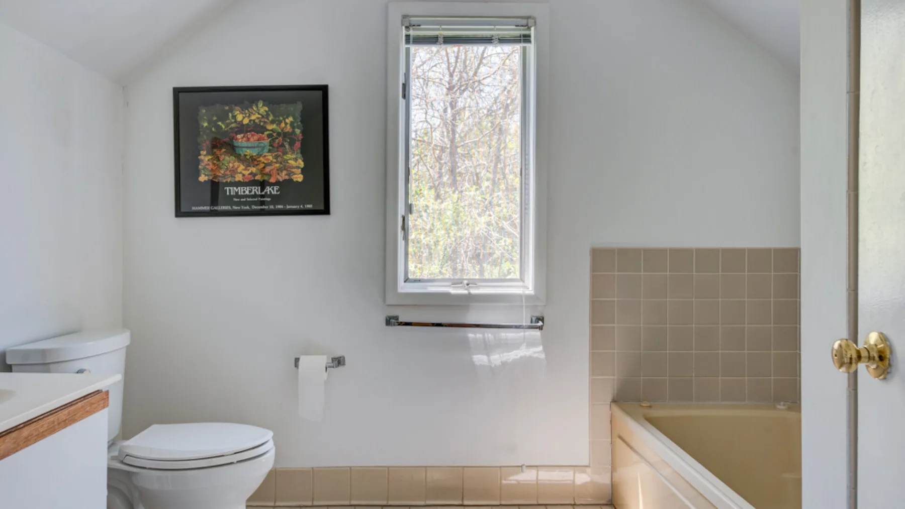A bright bathroom with a toilet, bathtub, and window.