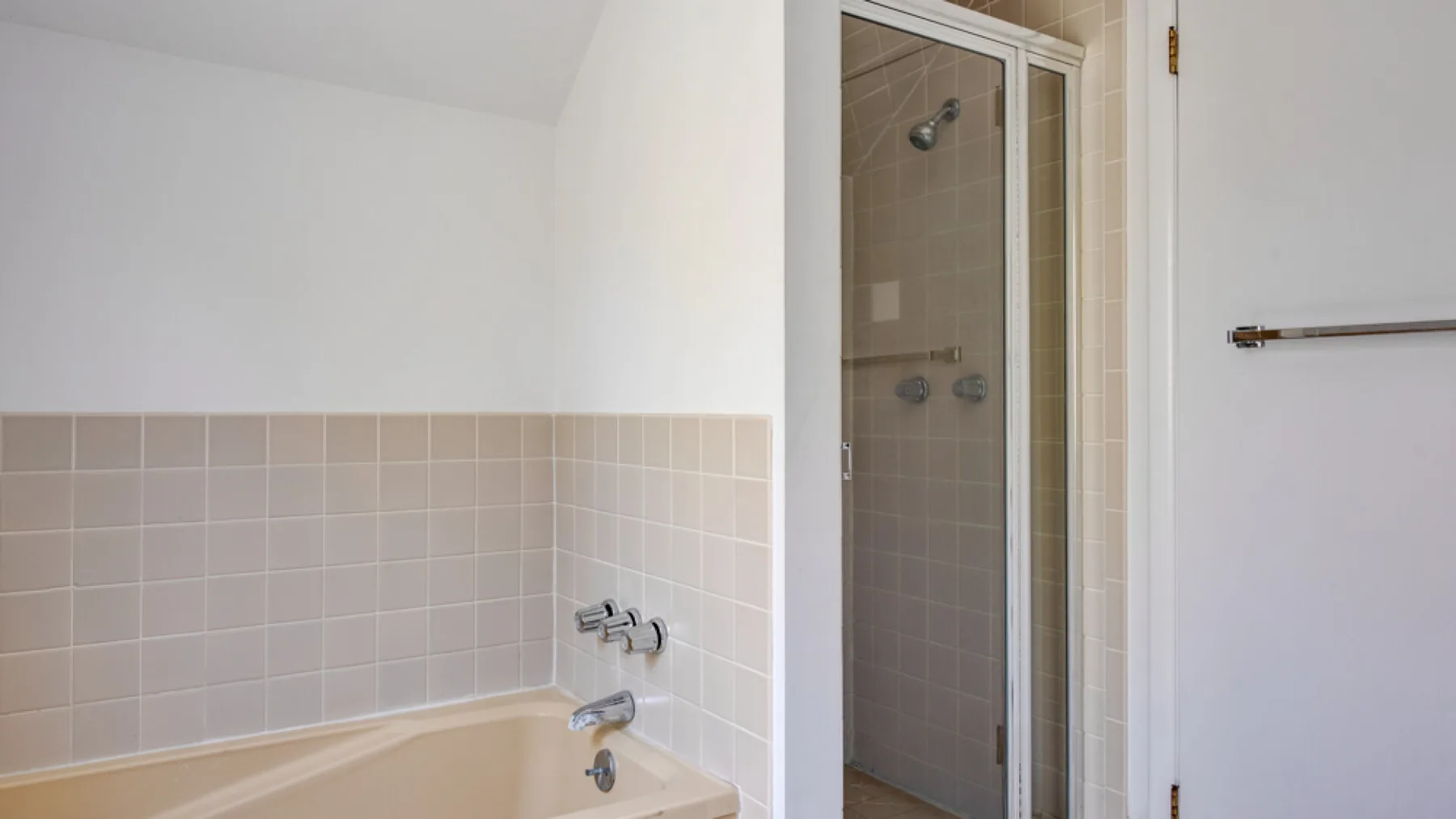 A bathroom with a bathtub, tiled walls, and a glass-enclosed shower.