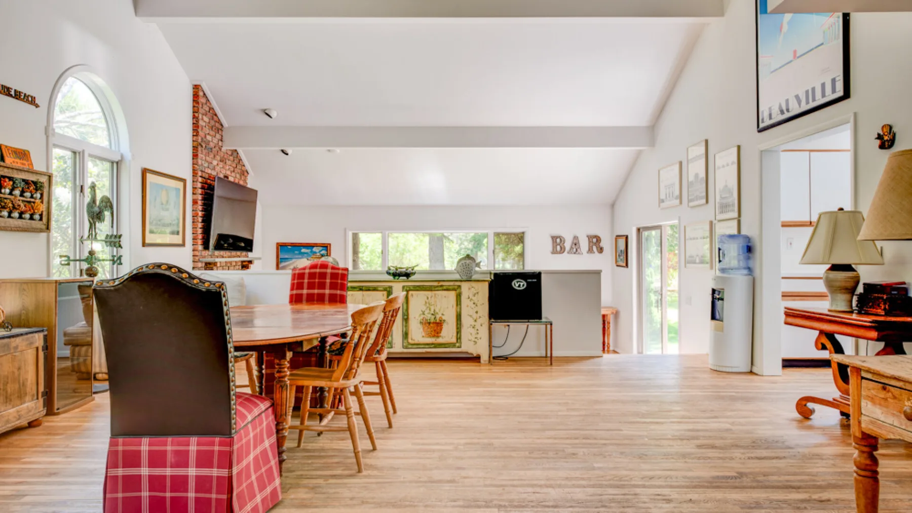 A bright open living and dining area with a table, seating, and large windows.