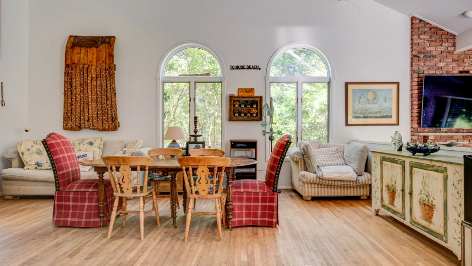 A bright living and dining area with a wooden dining table and arched windows.