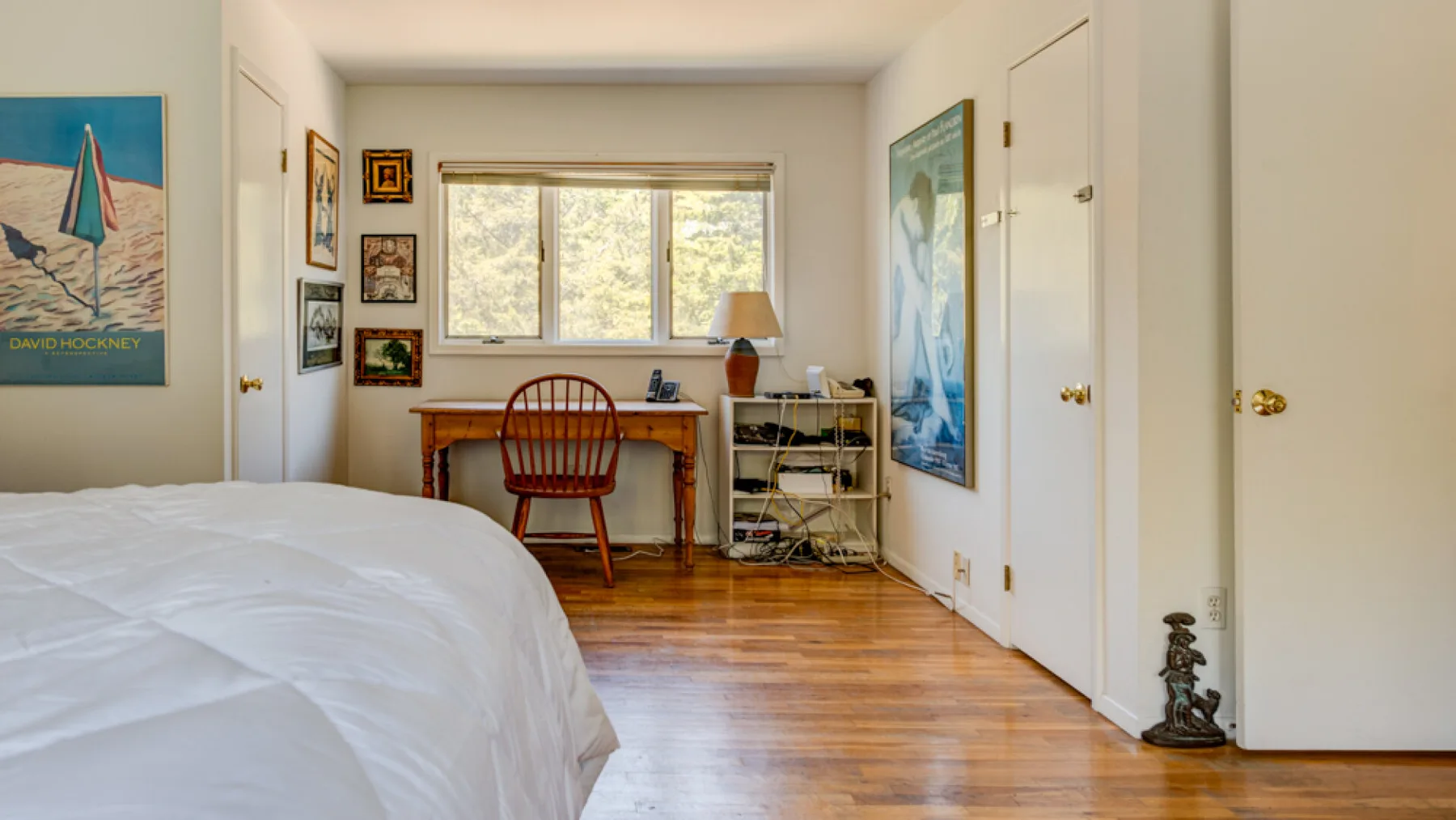 A bedroom with a bed, desk, and large window.