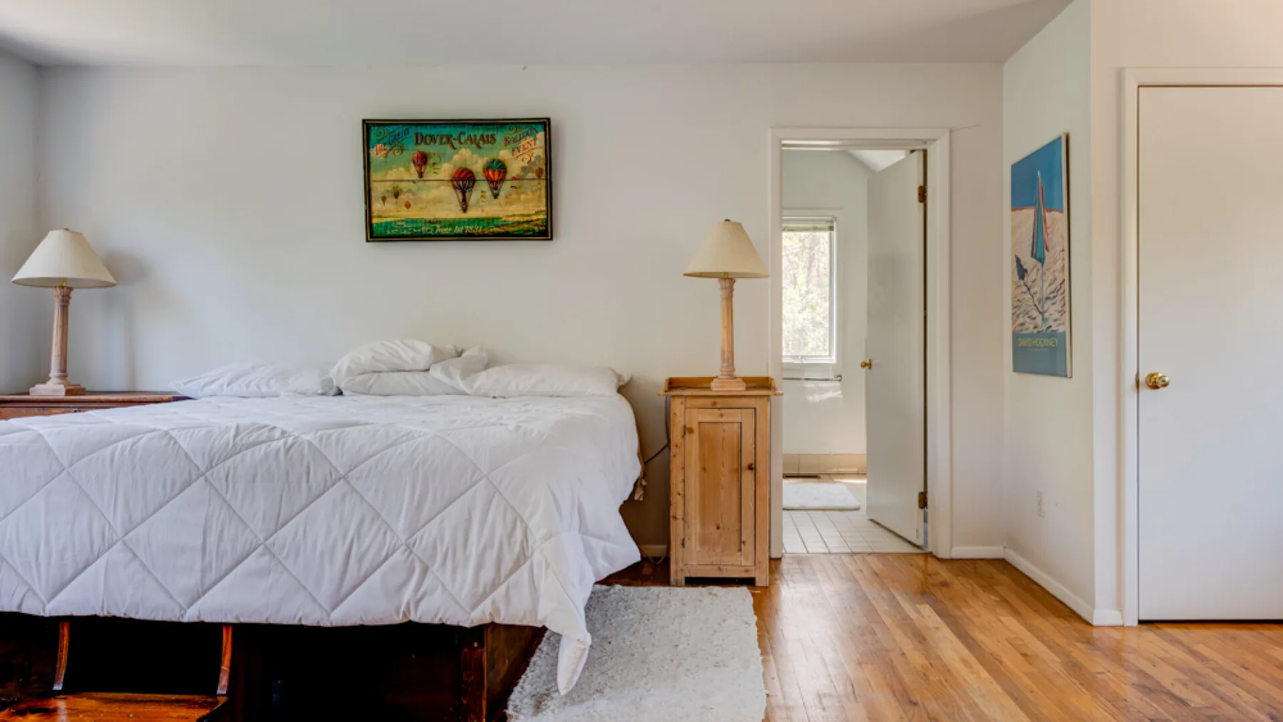 A bedroom with a neatly made bed, wooden bedside furniture, and wall art.