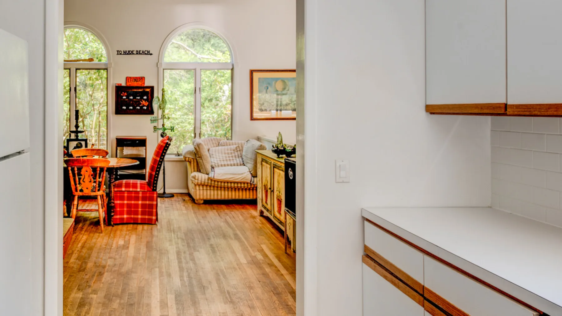 A bright living and dining area with seating, a table, and large windows.