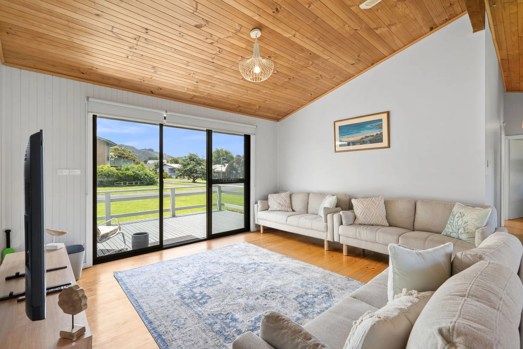 Living room with seating, a large rug, and sliding glass doors.