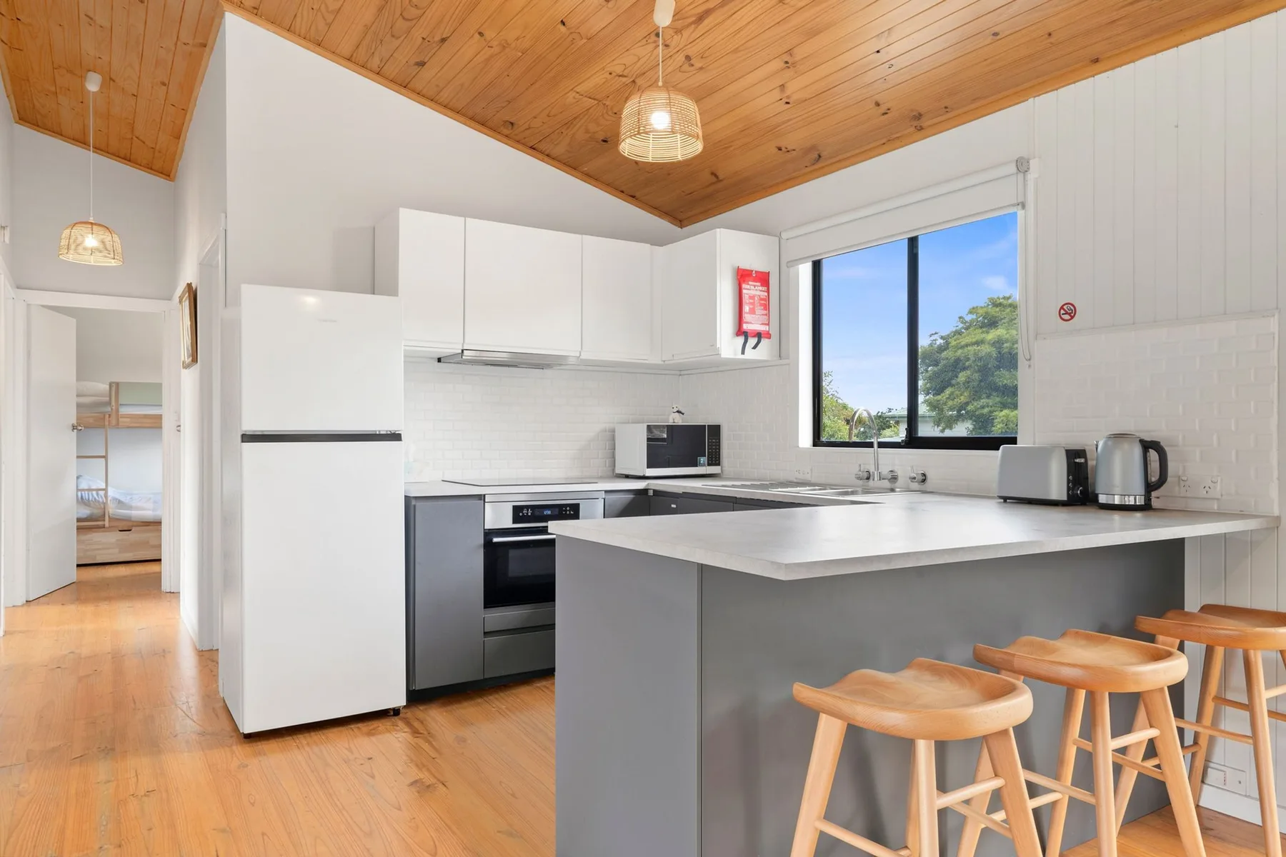 A bright kitchen with a large island and wooden bar stools.