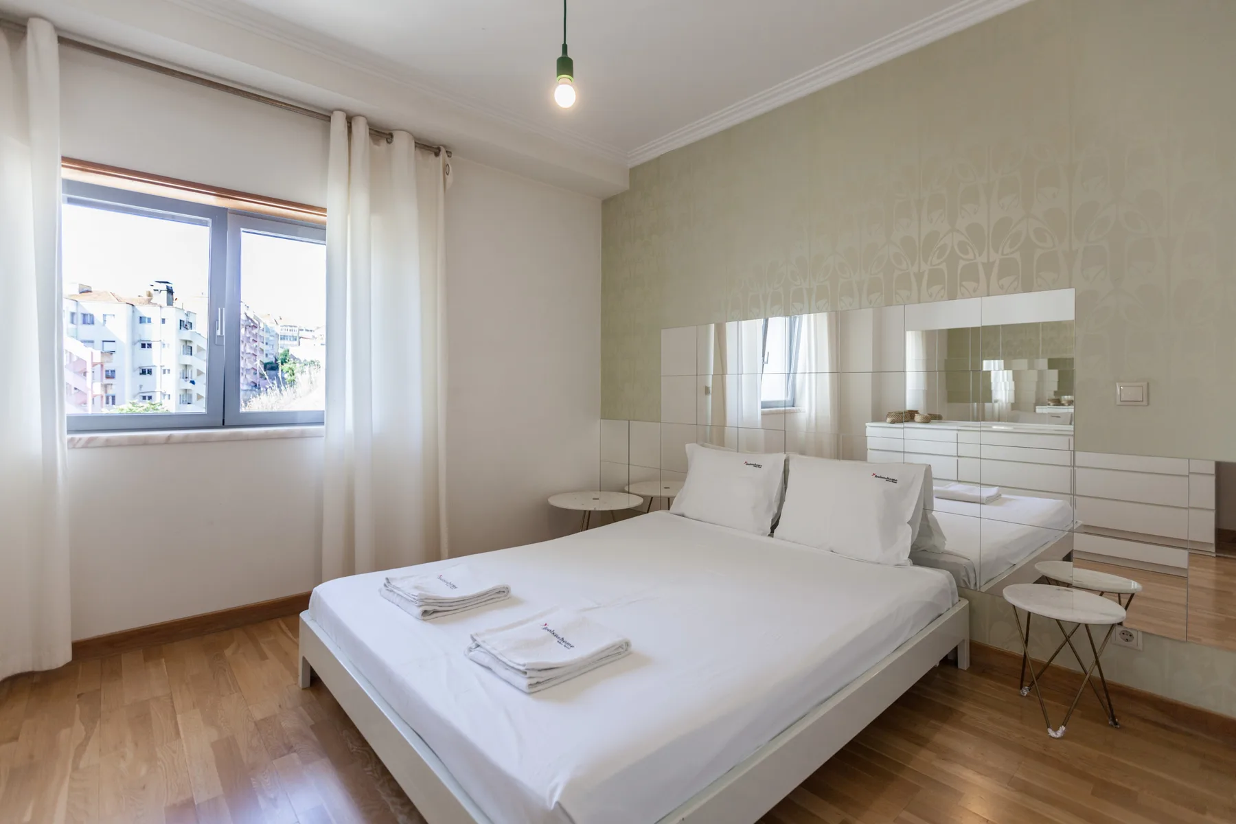 Dormitorio con una cama, paneles de espejo y una ventana.