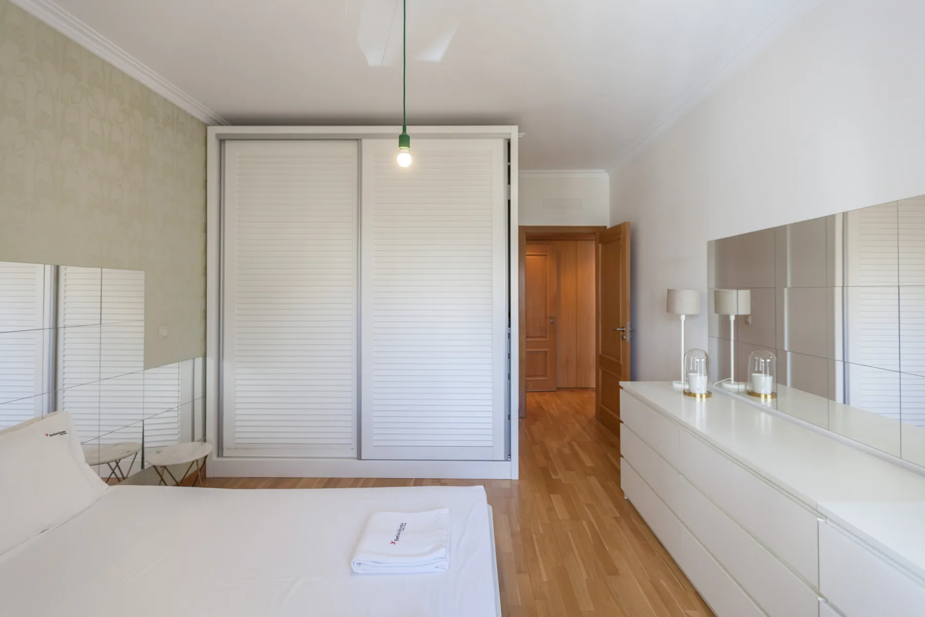 Un dormitorio con una cama, puertas correderas de armario y una cómoda alargada.