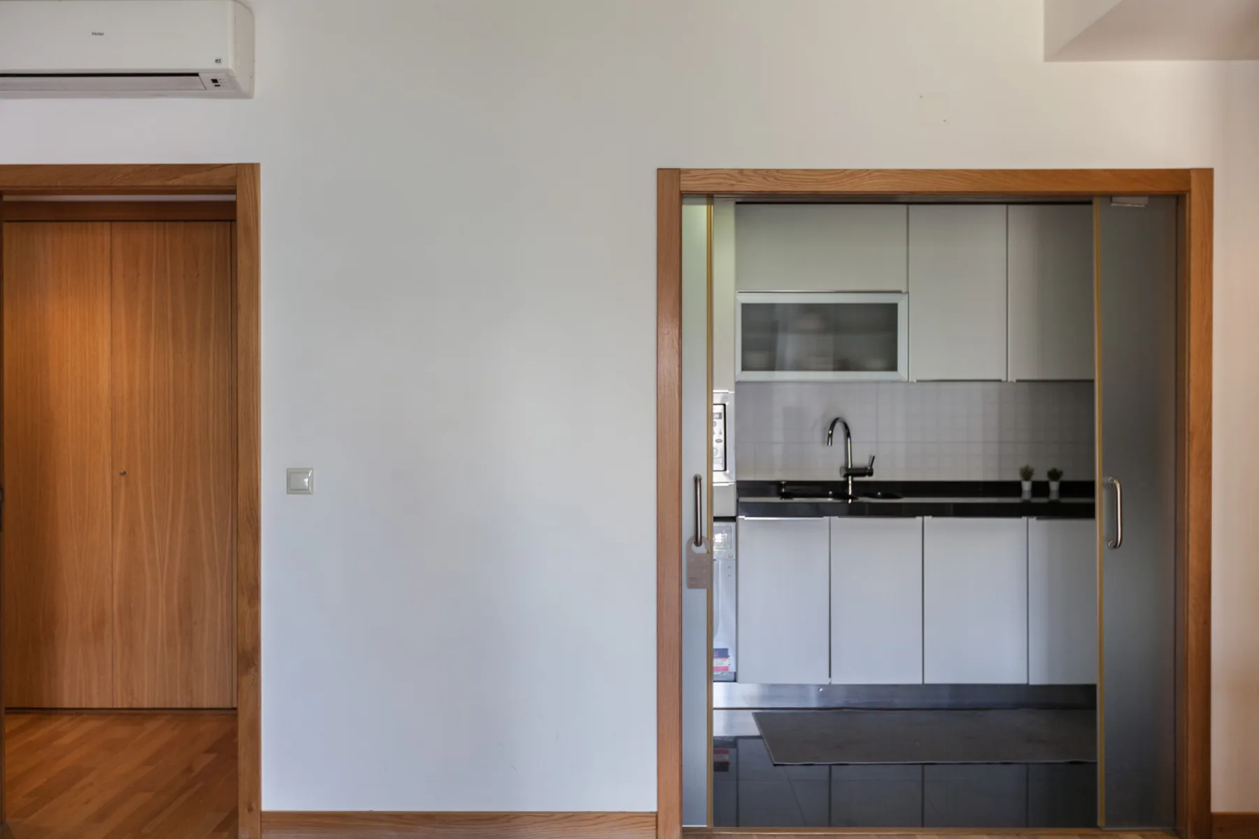 Se ve una cocina a través de una puerta, junto a una puerta de madera.