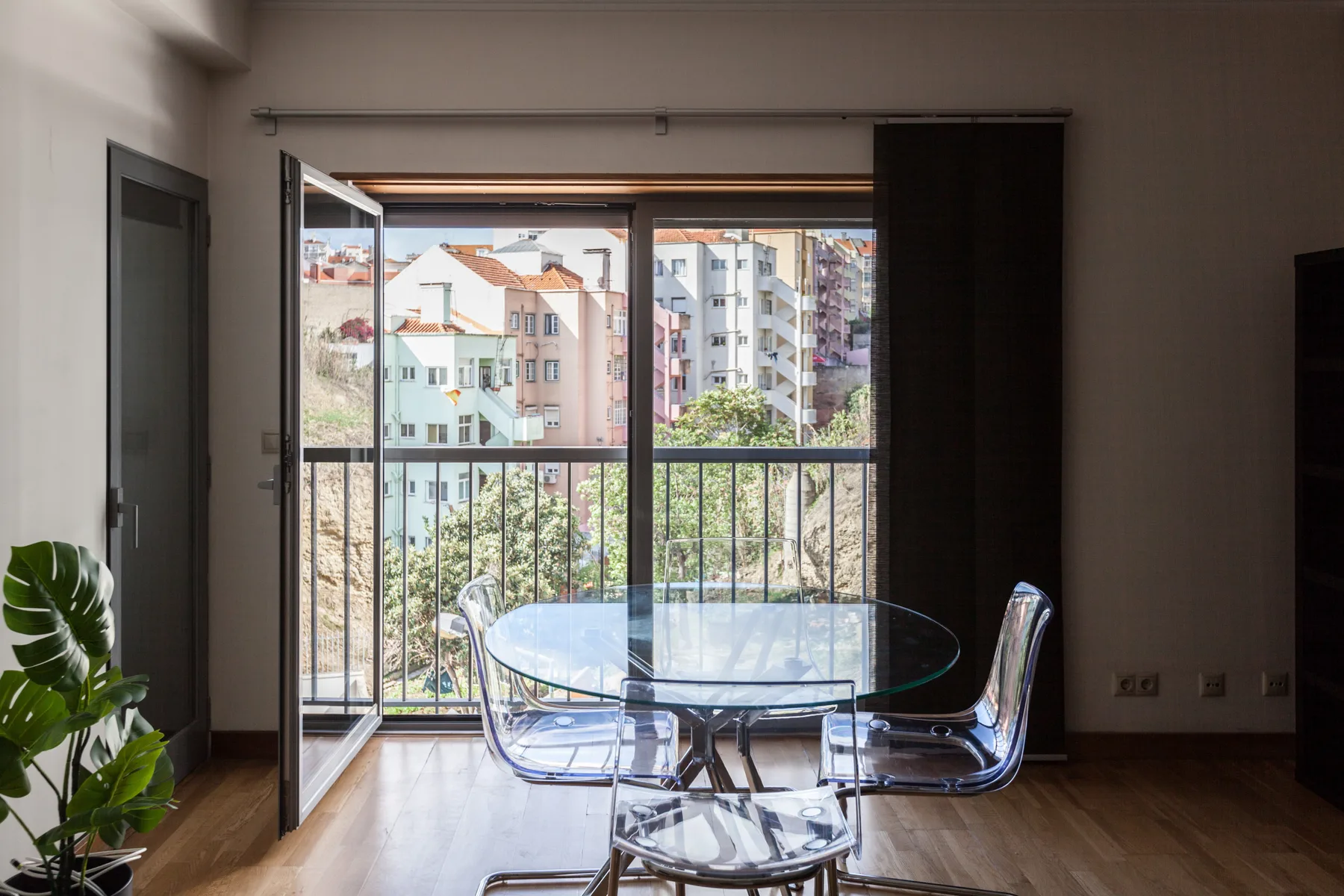Comedor con una mesa de vidrio y asientos junto a una ventana amplia.