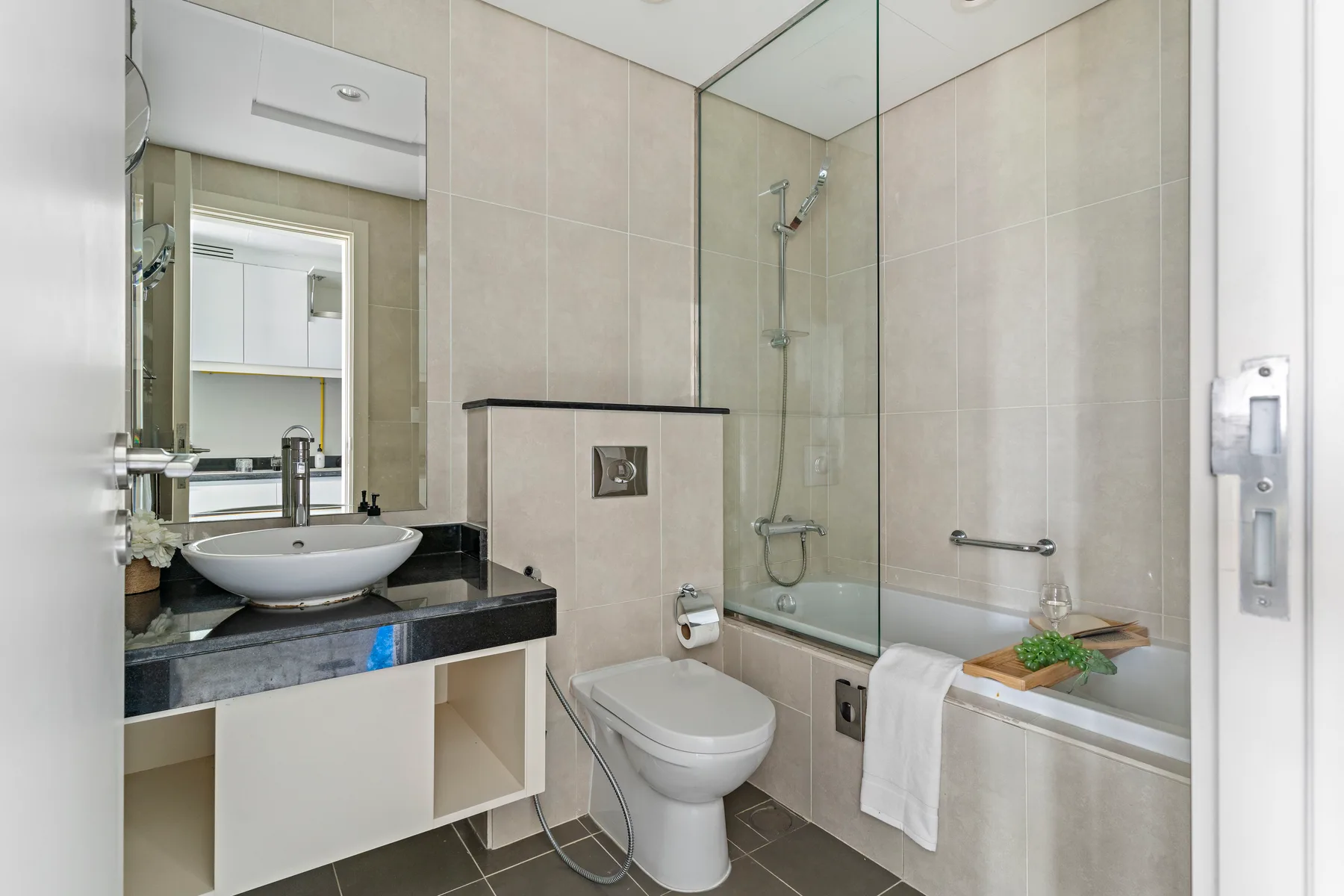 A tiled bathroom with a sink, toilet, and glass shower enclosure.