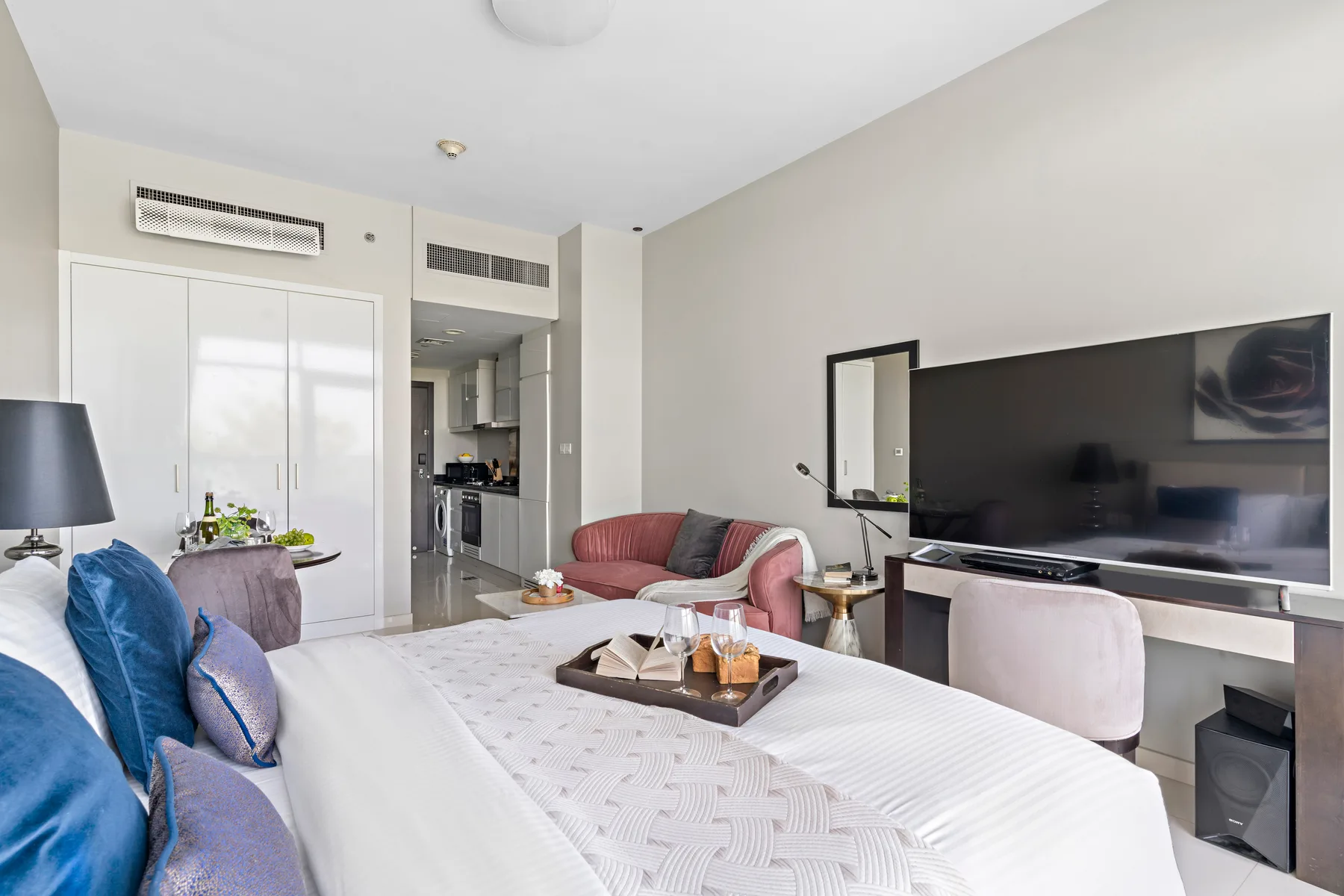 A bedroom with a large bed, seating, and a television on a low console.