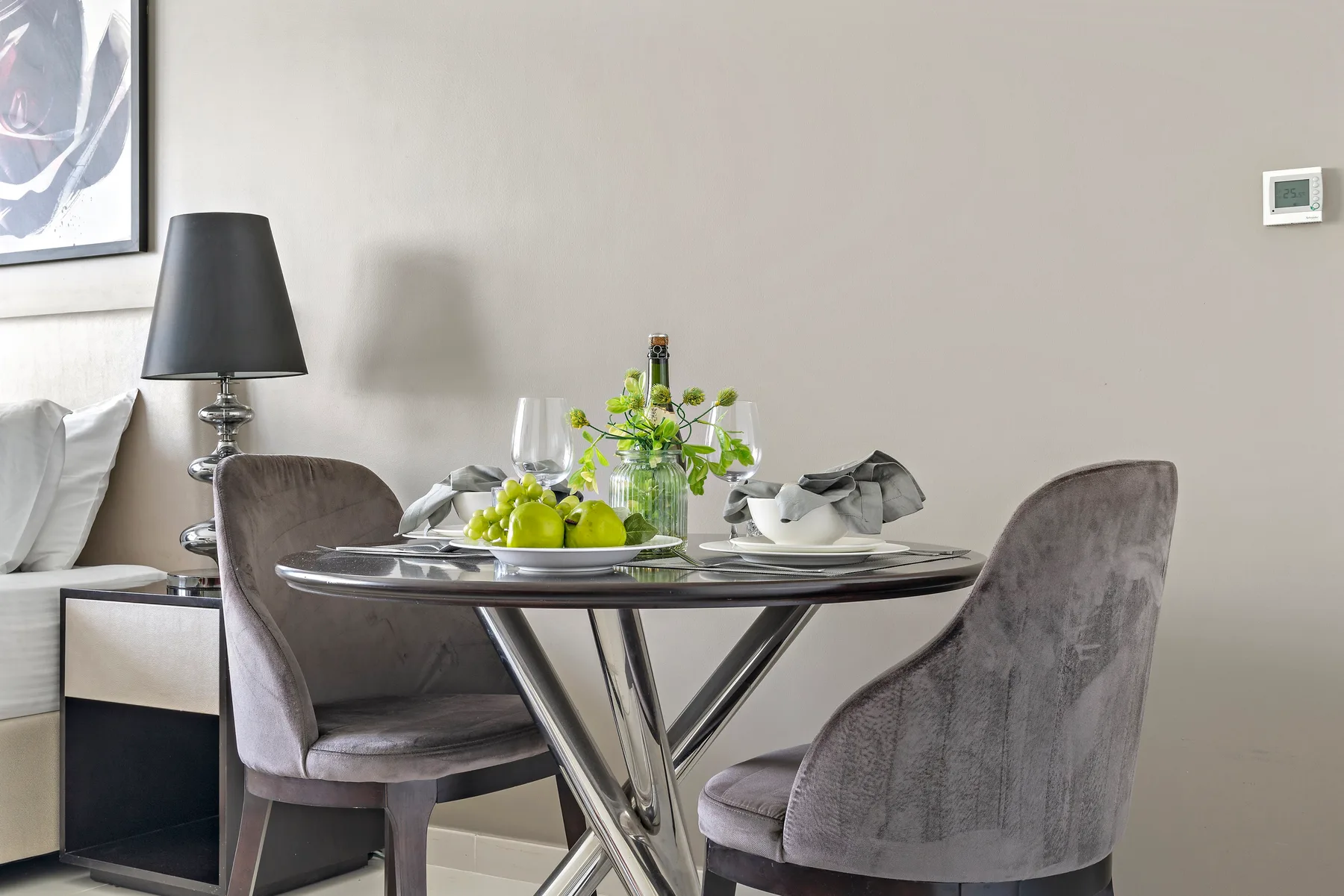 A dining area with a round table set with dishes and fruit.