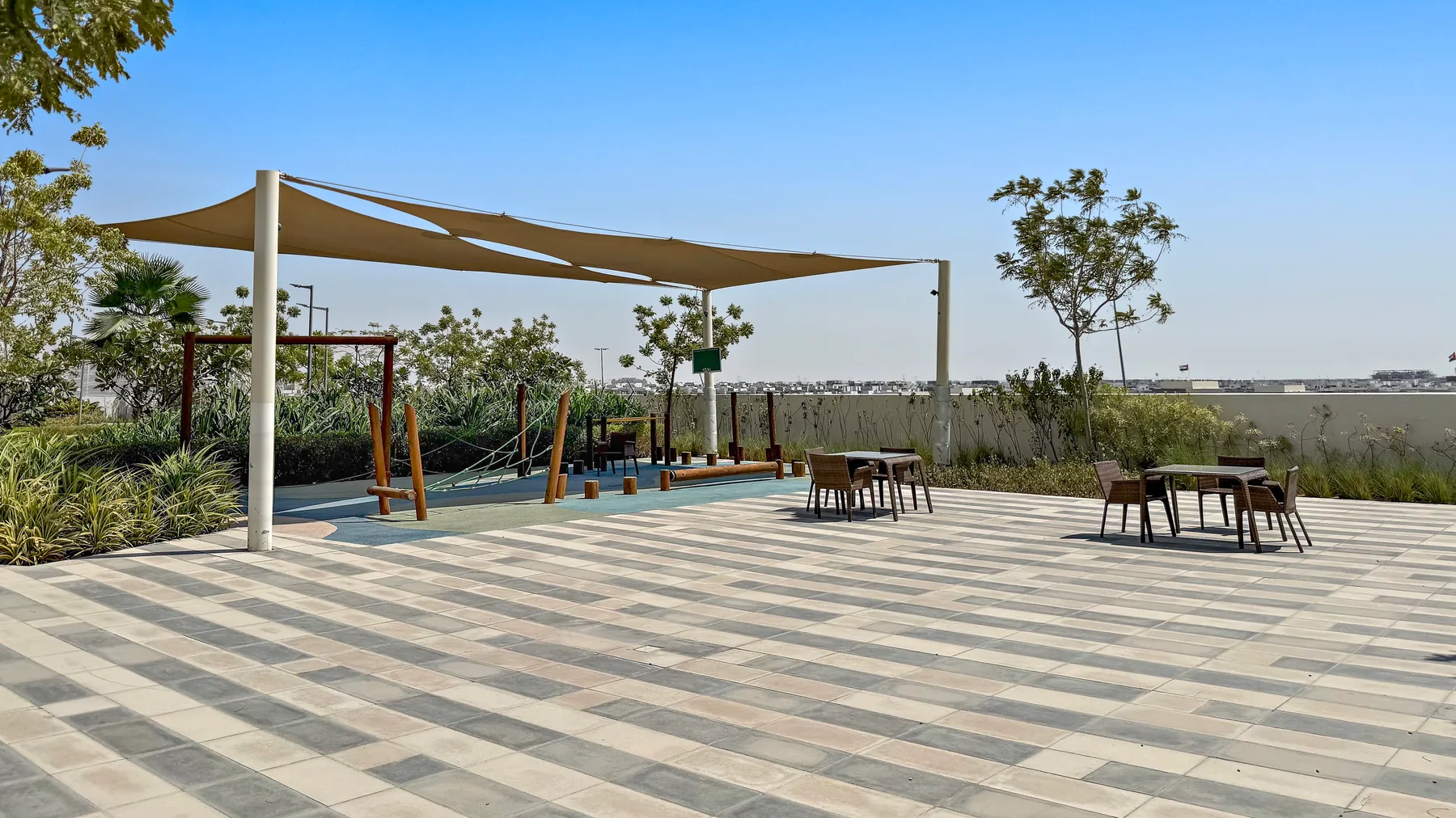 An outdoor paved patio has shaded seating and a garden swing area.