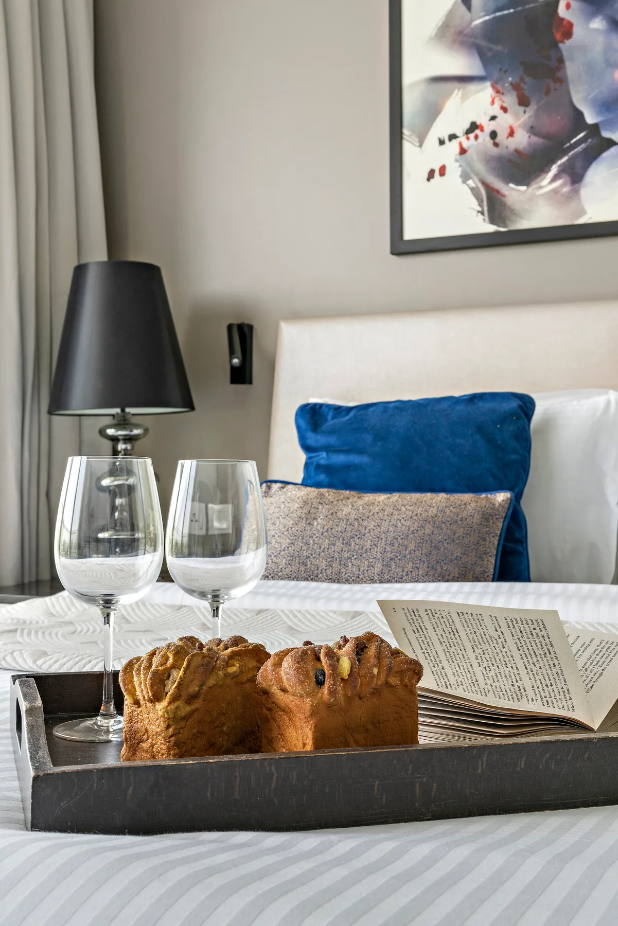 A bedroom with a bed, colorful cushions, and a tray of bread on the bed.