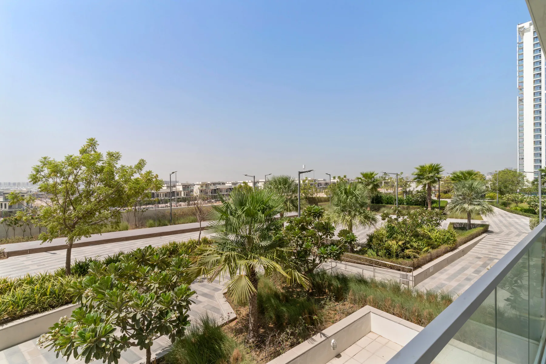 A landscaped rooftop terrace features planted gardens, walking paths, and a glass railing.