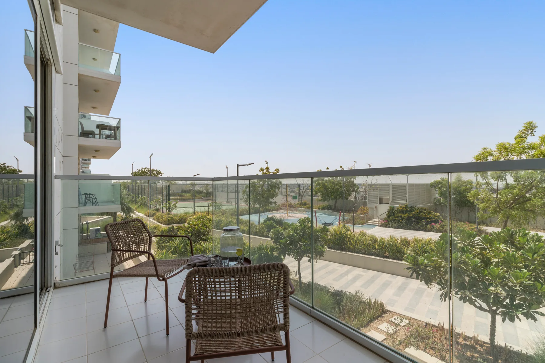 A balcony with seating overlooks landscaped gardens and a swimming pool.