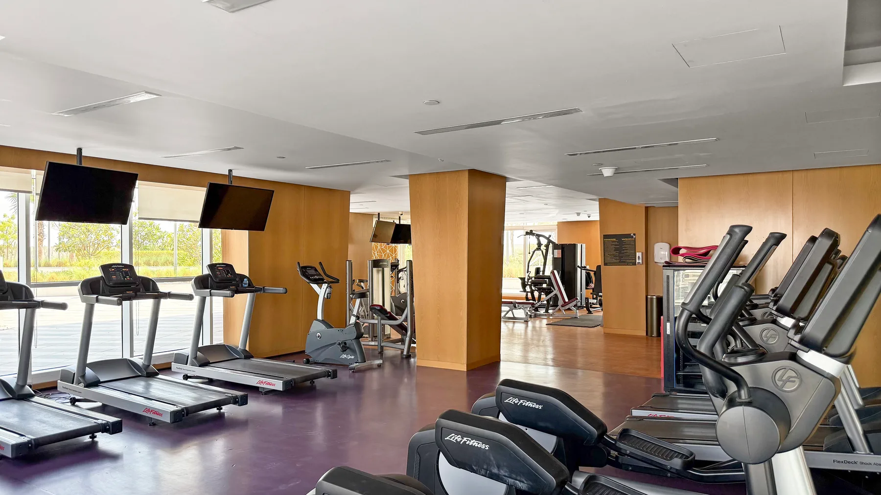 A gym with treadmills and other exercise equipment arranged across the room.