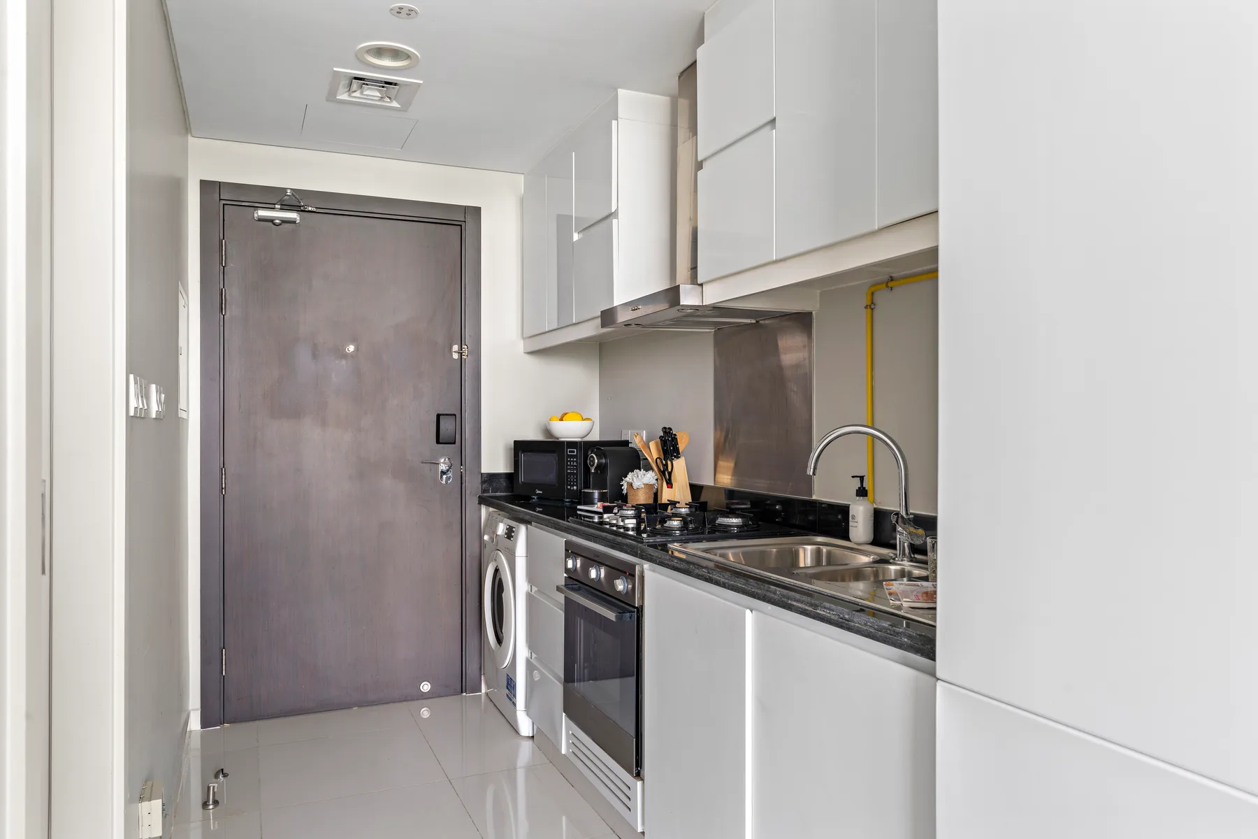 A compact kitchen with white cabinets and a dark countertop.