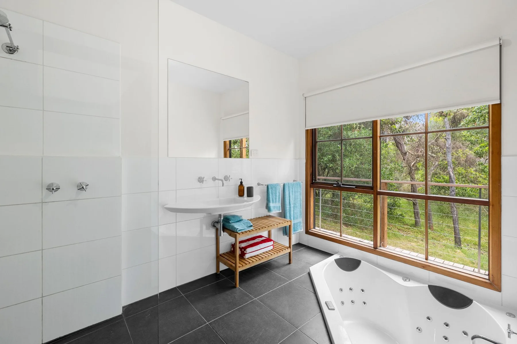 Un baño luminoso con lavabo, una ventana amplia y una bañera.