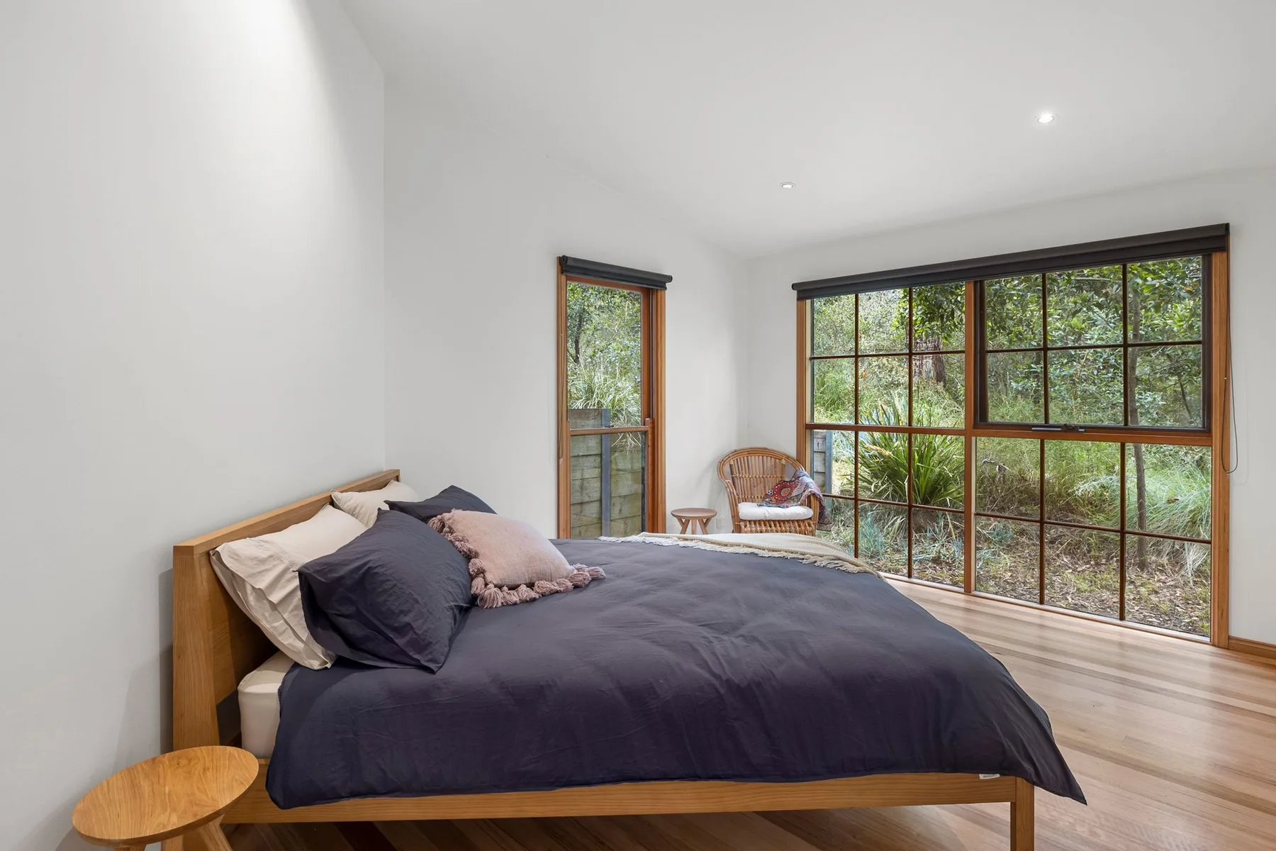 Un dormitorio con una cama y grandes ventanas que dan a la vegetación.