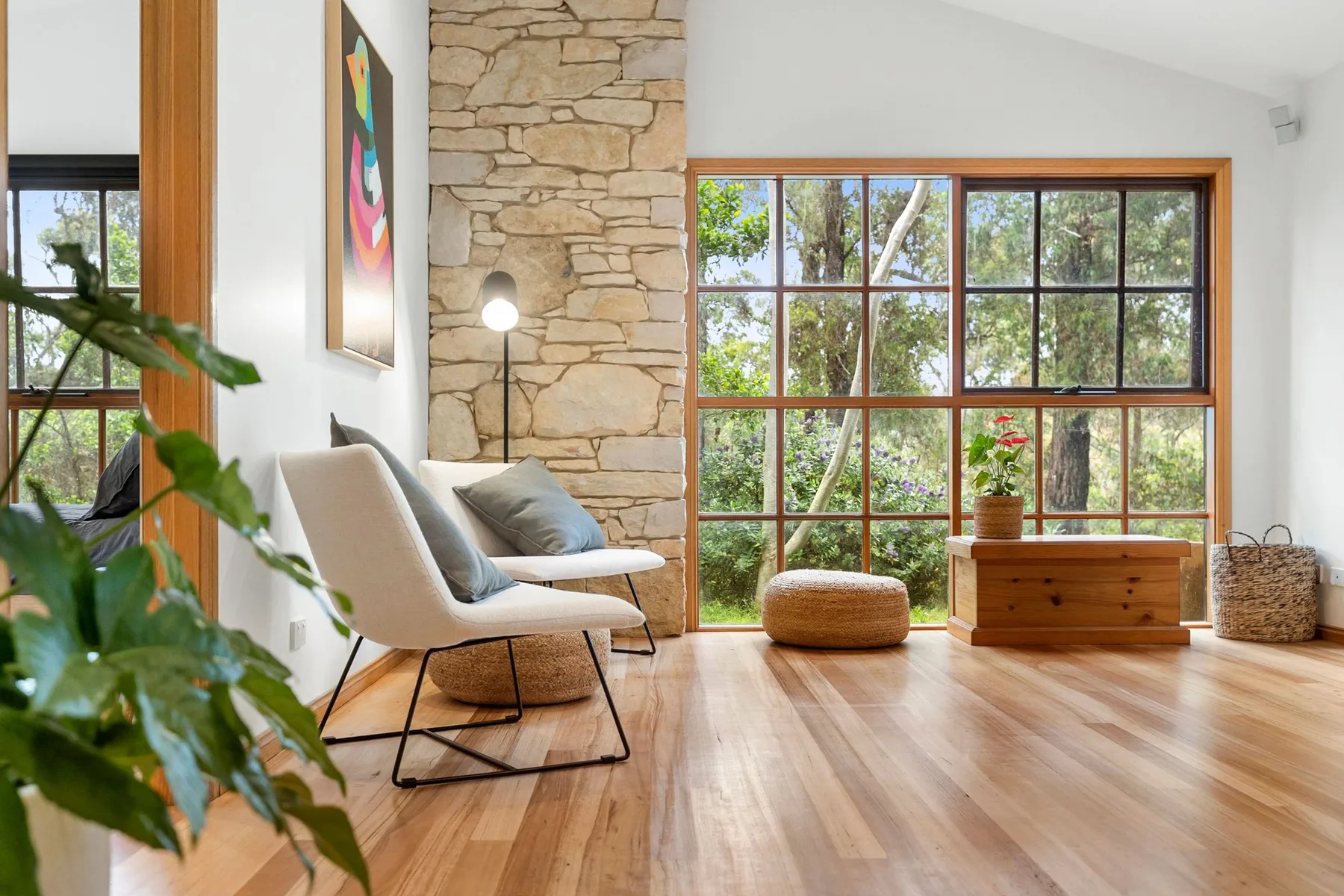 Una luminosa sala de estar con asientos, una ventana amplia y una pared de piedra.