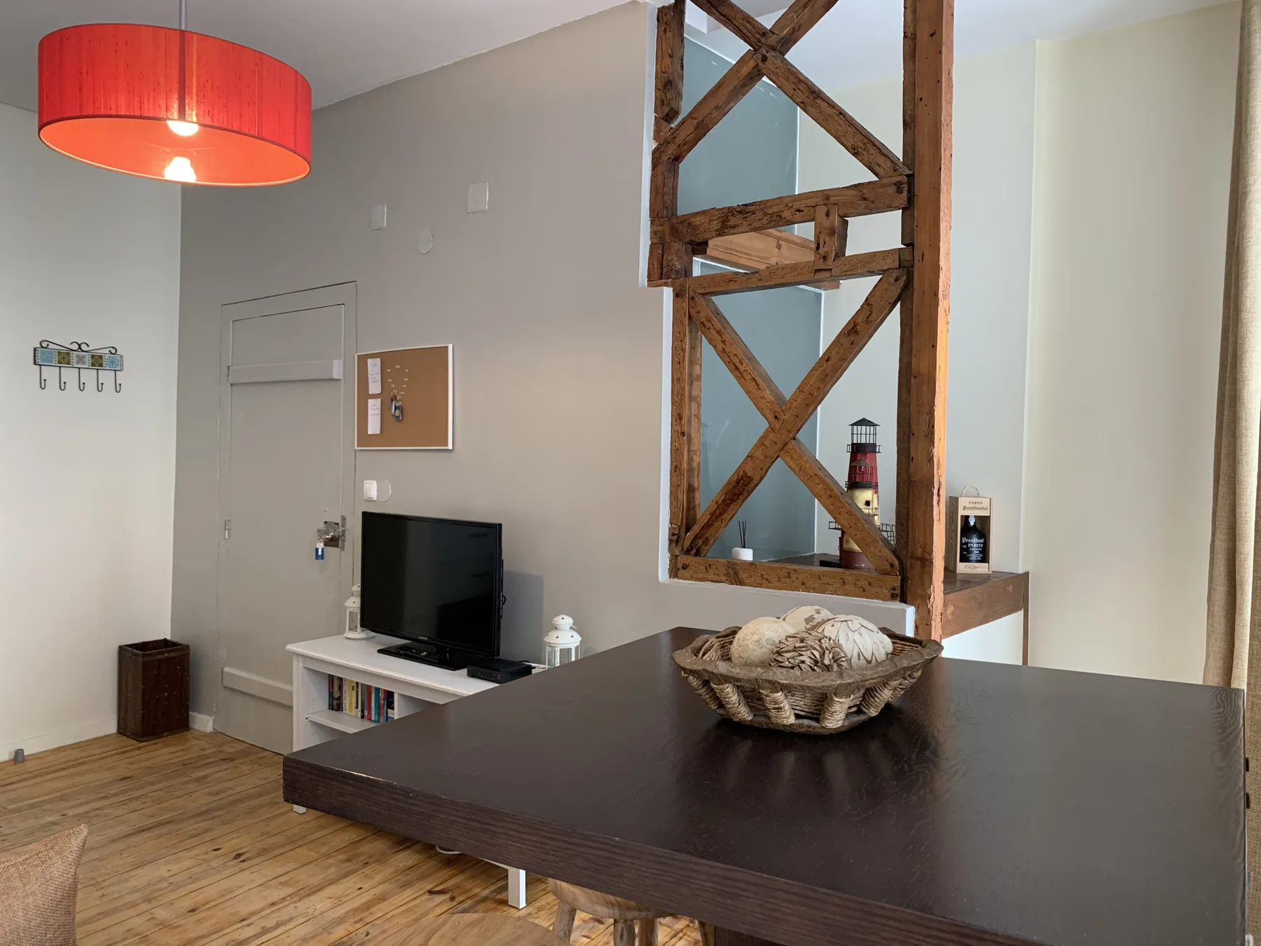 A living area with a television, dark table, and exposed wooden beams.