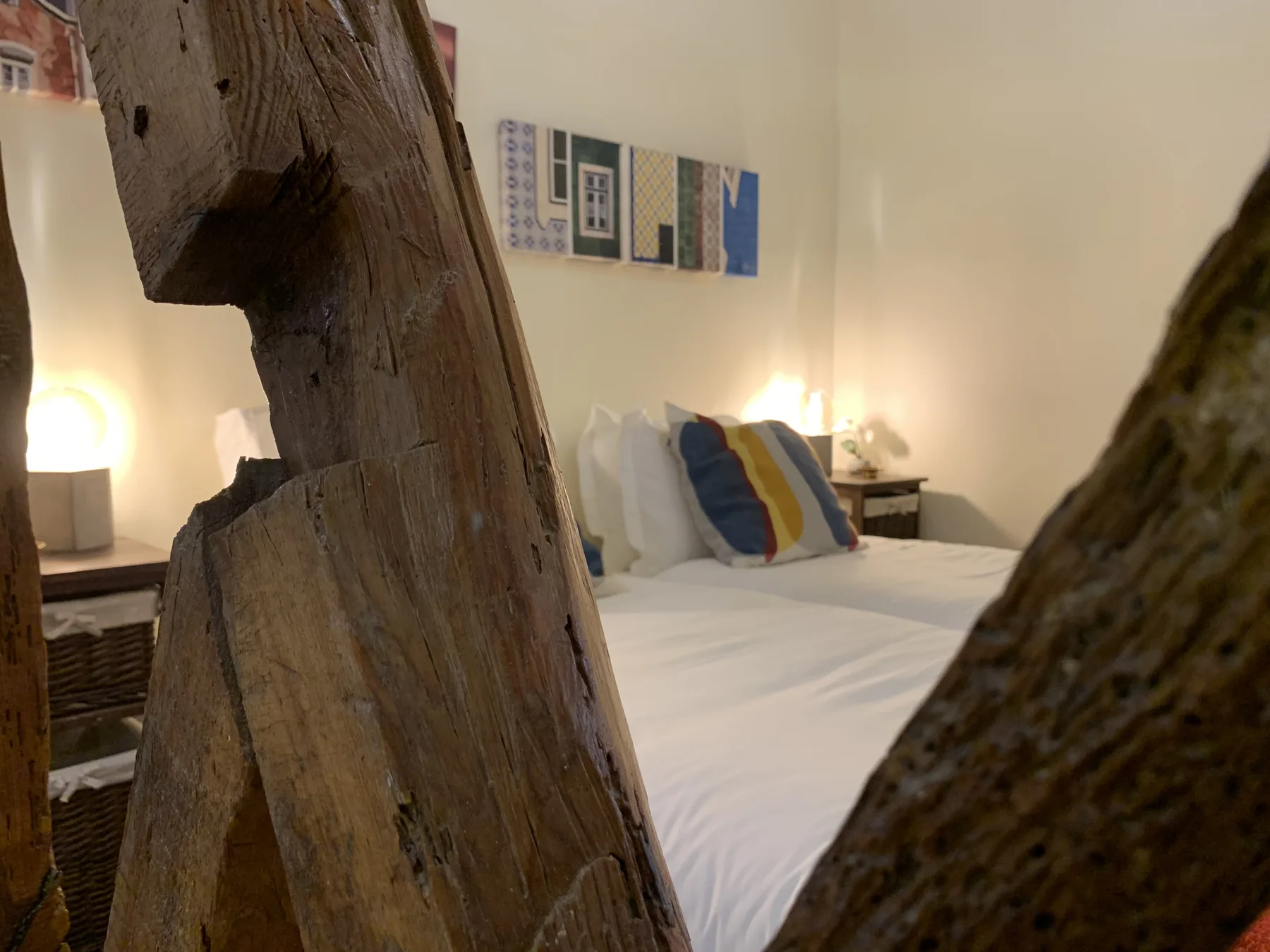 A bedroom with a neatly made bed and colorful wall art.